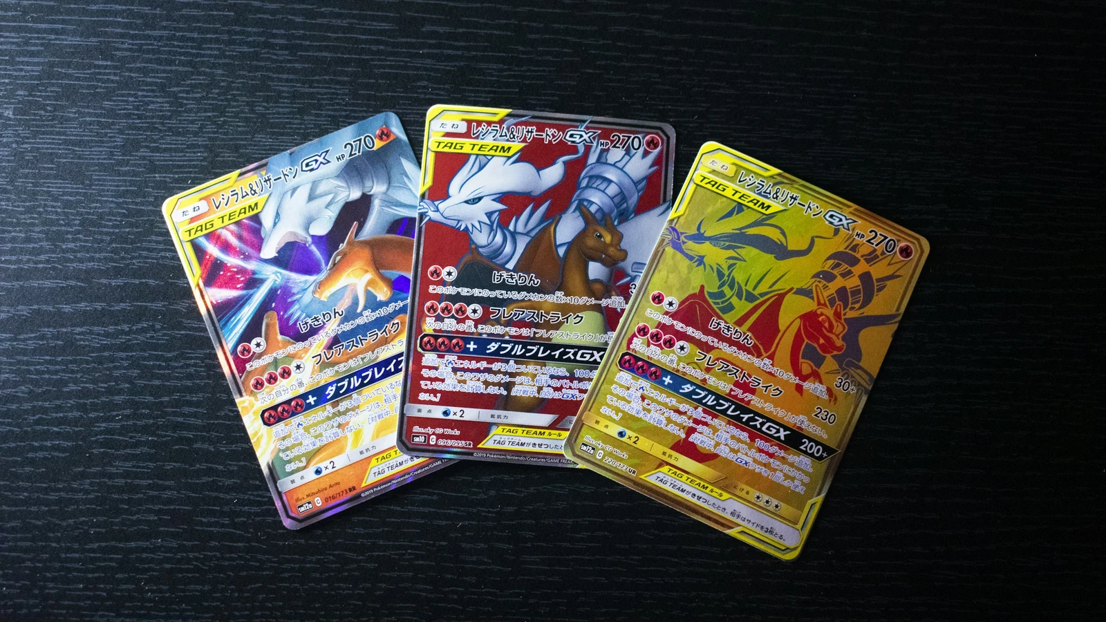 Drei japanische Pokémon-Karten mit verschiedenen Versionen desselben Figurenpaars auf einer dunklen Tischfläche